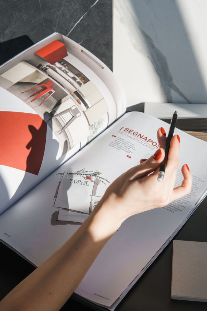 Hand mit Stift über einem redaktionellen Magazinlayout