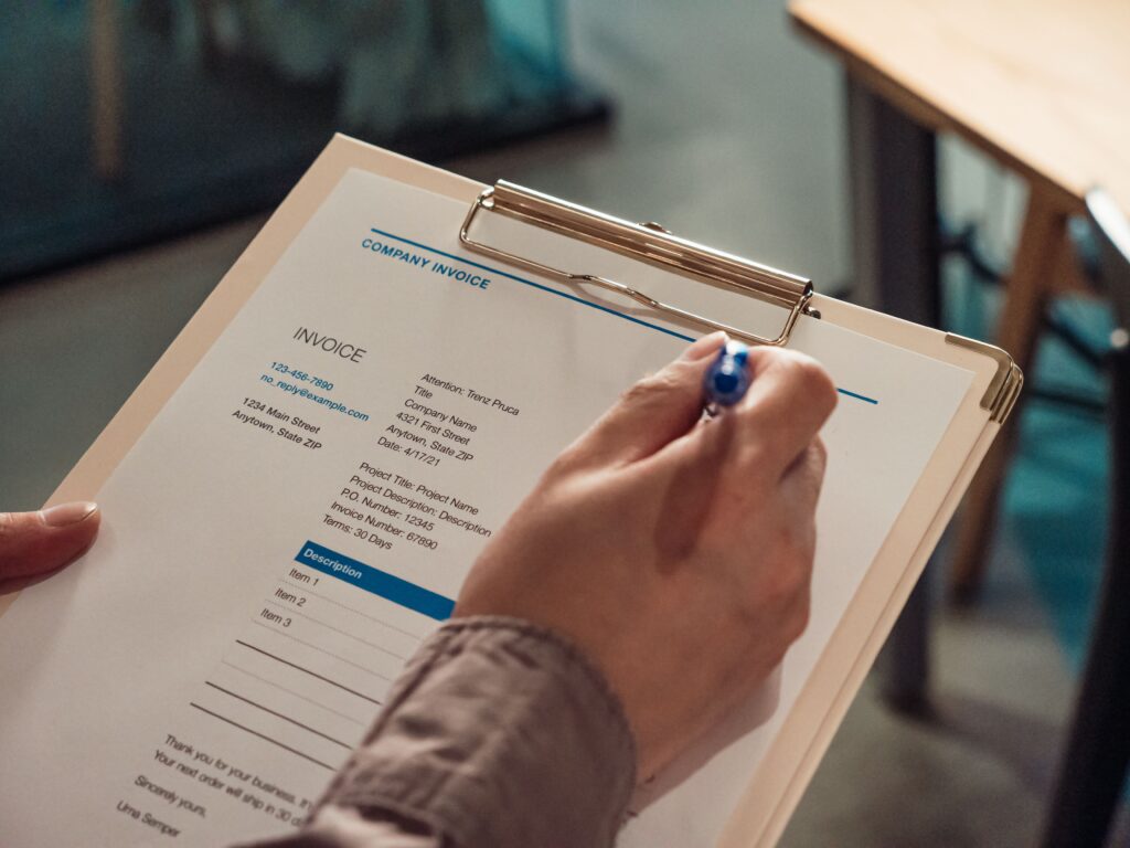 Hand prüft ein Formular mit Stift und Klemmbrett
